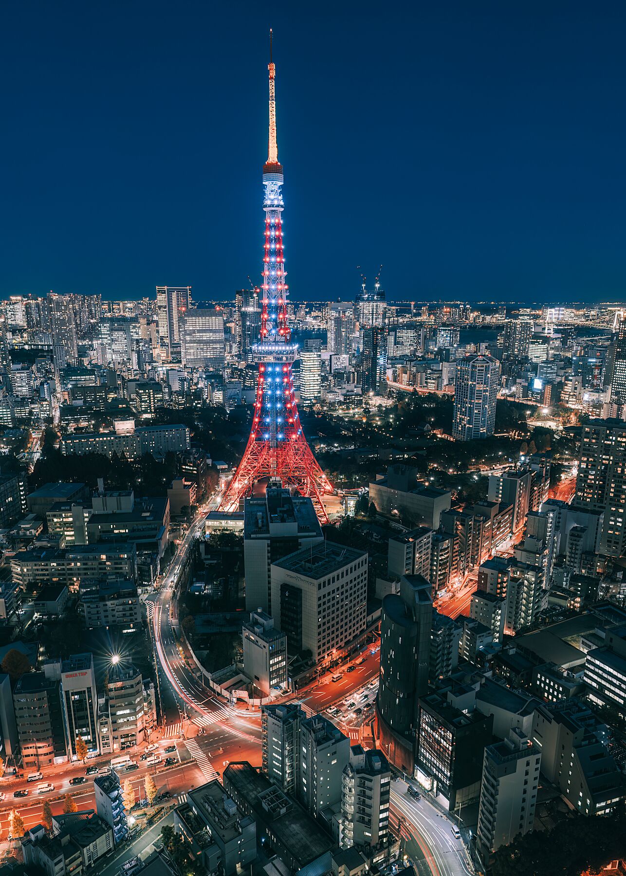 Tokyo Tower illuminated at night, surrounded by the city skyline.