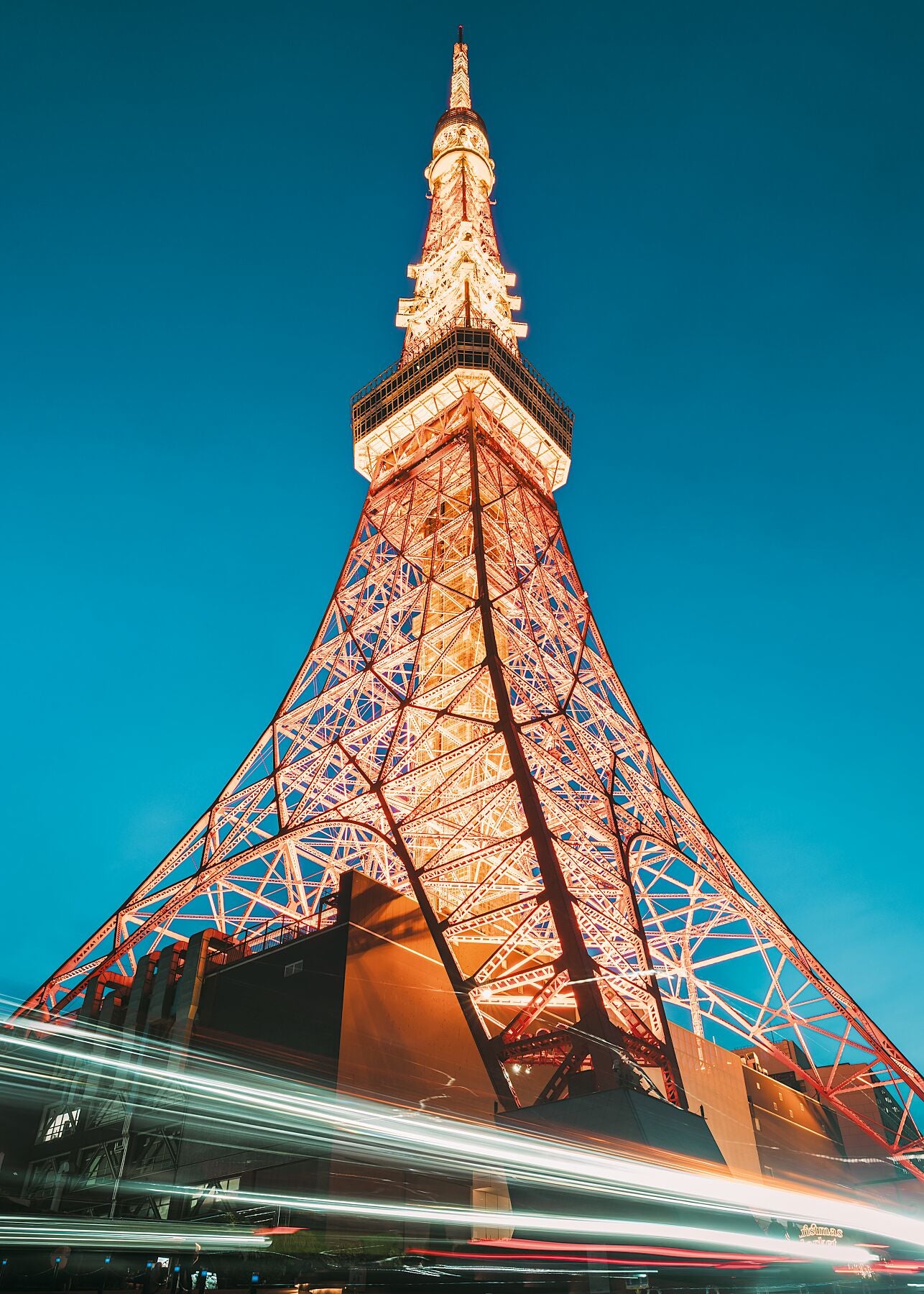 A striking low-angle view of Tokyo Tower just after sunset, with a deep blue sky.